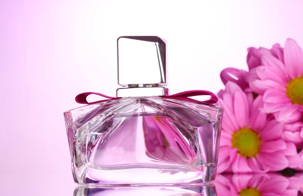 Жіночі парфуми в красивій пляшці і квіти на рожевому фоні — стокове фото