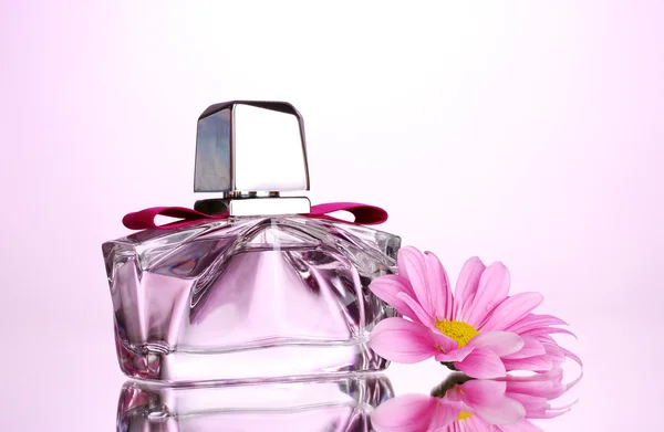 Жіночі парфуми в красивій пляшці і квітці на рожевому фоні — стокове фото