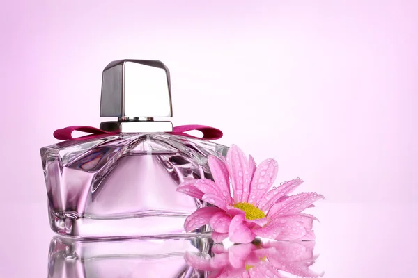 Perfume das mulheres em bela garrafa e flor no fundo rosa — Fotografia de Stock