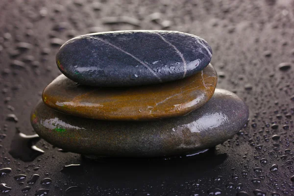 Wellness-Steine mit Wassertropfen auf schwarzem Hintergrund — Stockfoto
