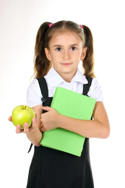 Hermosa niña en uniforme escolar, libro y manzana aislado en blanco — Foto de Stock