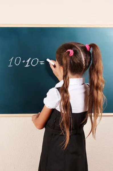 Schönes kleines Mädchen schreibt auf Klassenzimmertafel — Stockfoto