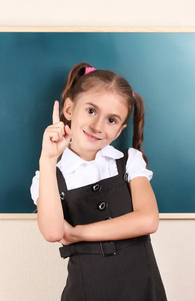 Beautiful little girl standing near blackboard in the classroom — Stock Photo, Image
