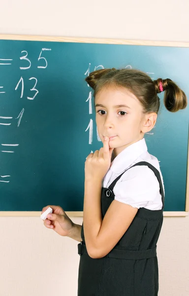 Linda menina escrevendo no quadro de sala de aula — Fotografia de Stock