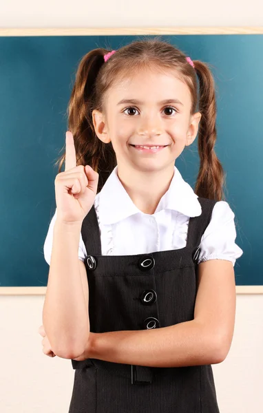 Linda menina de pé perto de quadro negro na sala de aula — Fotografia de Stock