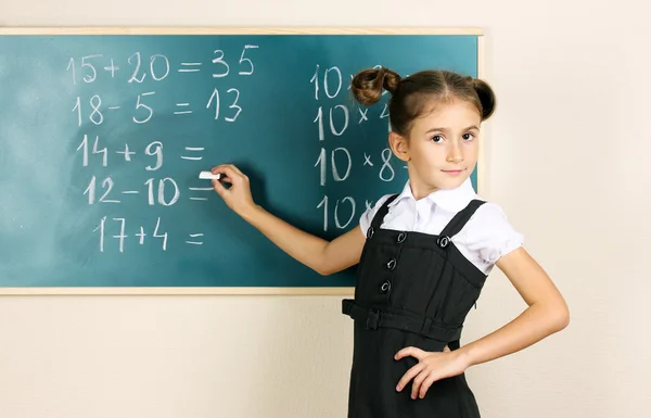 Linda menina escrevendo no quadro de sala de aula — Fotografia de Stock