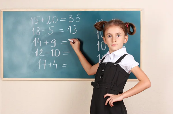 Beautiful little girl writing on classroom board — Stock Photo, Image