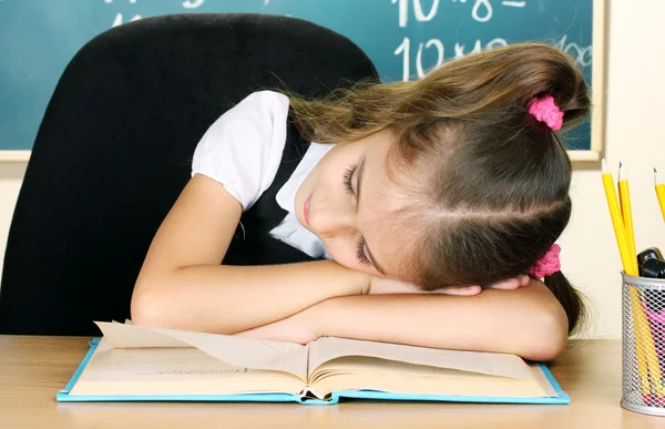 Petite écolière dormir dans la salle de classe près de tableau noir — Photo