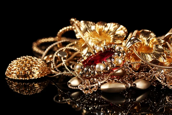 Různé zlaté šperky na černém pozadí — Stock fotografie