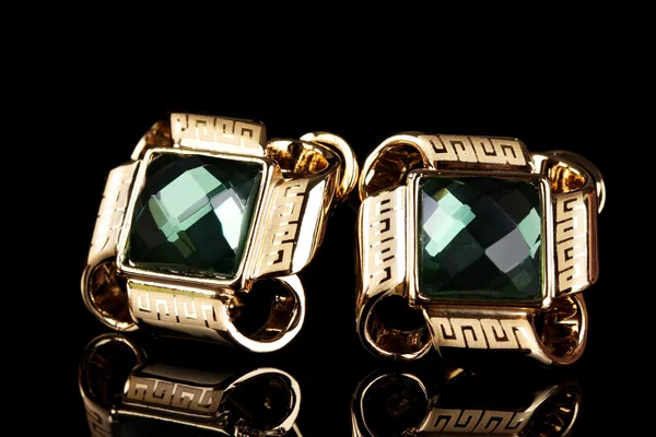 Krásné zlaté náušnice s emerald na černém pozadí — Stock fotografie