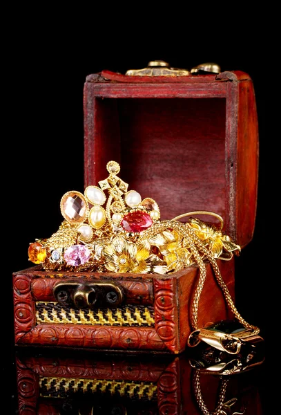 Drewniana skrzynia pełna Biżuteria złota na czarnym tle — Zdjęcie stockowe