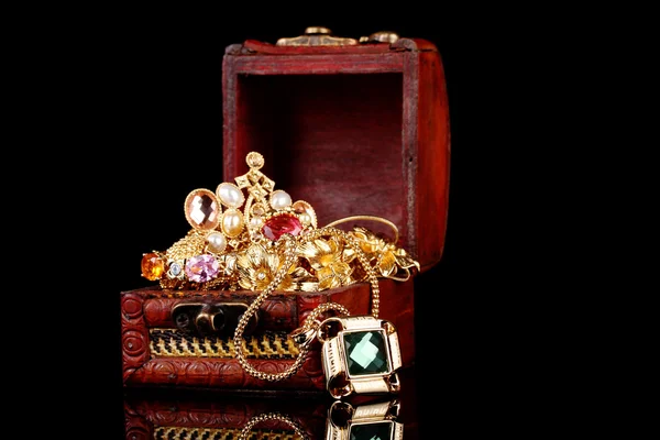 stock image Wooden chest full of gold jewelry on black background