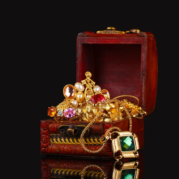 Dřevěná truhla plná zlatých šperků na černém pozadí — Stock fotografie