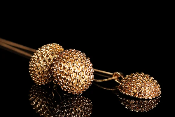 Krásné zlaté náušnice a náhrdelník na černém pozadí — Stock fotografie