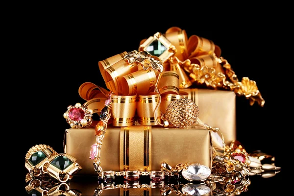 Çeşitli altın takı ve siyah arka plan üzerinde hediyeler — Stok fotoğraf