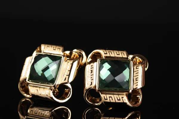 Hermosos pendientes de oro con esmeralda sobre fondo negro —  Fotos de Stock