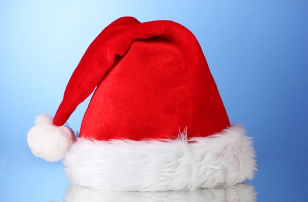Schöne Weihnachtsmütze auf blauem Hintergrund — Stockfoto