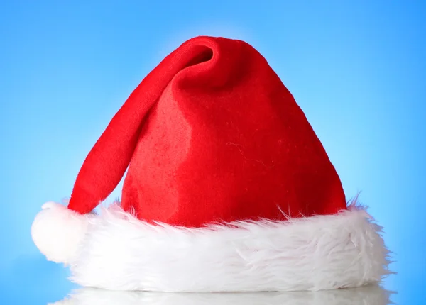 Schöne Weihnachtsmütze auf blauem Hintergrund — Stockfoto