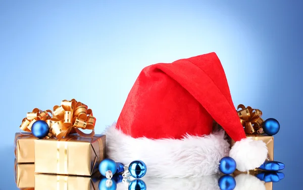 Vackra jul hatt, gåvor och julgranskulor på blå bakgrund — Stockfoto
