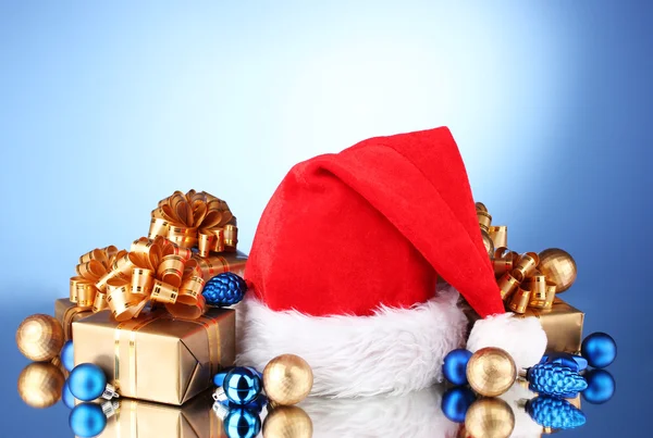 Όμορφο καπέλο Χριστούγεννα, δώρα και Χριστούγεννα μπάλες σε μπλε φόντο — Φωτογραφία Αρχείου