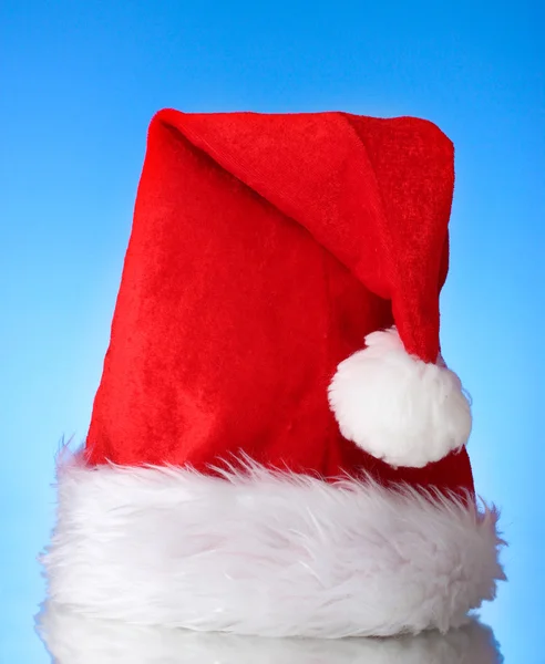 หมวกคริสต์มาสที่สวยงามบนพื้นหลังสีฟ้า — ภาพถ่ายสต็อก