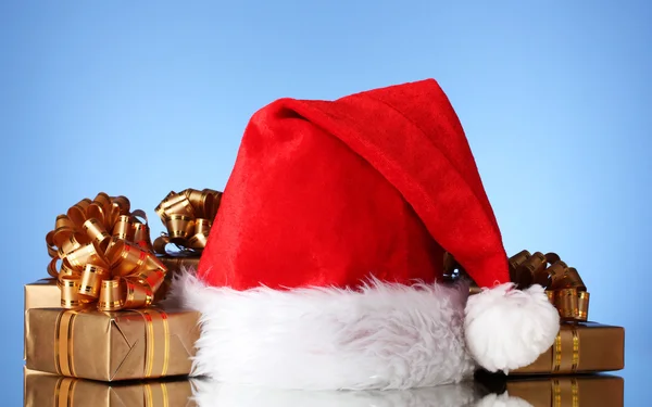 Hermoso sombrero de Navidad y regalos sobre fondo azul — Foto de Stock