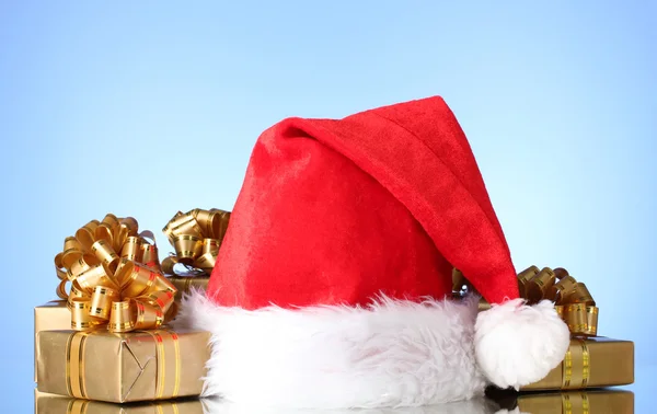 아름 다운 크리스마스 모자와 파란색 배경에 선물 — 스톡 사진