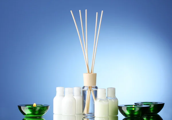 Bottle of air freshener and candles on blue background — Stock Photo, Image