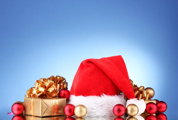 Szép karácsonyi kalapot, ajándékok és karácsonyi golyókat a kék háttér — Stock Fotó