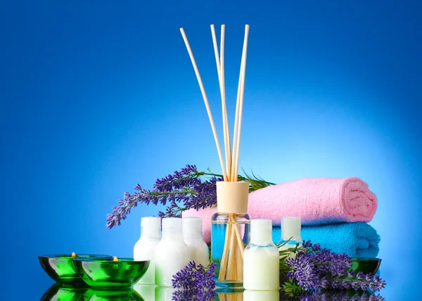 Бутылка освежителя воздуха, лаванда, полотенца и свечи на синем фоне — стоковое фото