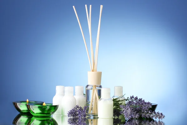 Bottiglia di deodorante, lavanda e candele su sfondo blu — Foto Stock