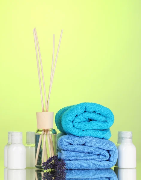 Fles luchtverfrisser, lavendel en handdoeken op groene achtergrond — Stockfoto