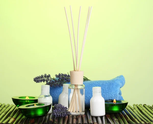 Oda spreyi, şişe, havlu ve bambu mat yeşil zemin üzerine mumlar — Stok fotoğraf