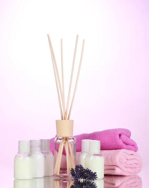 Botella de ambientador, lavanda y toallas sobre fondo rosa — Foto de Stock