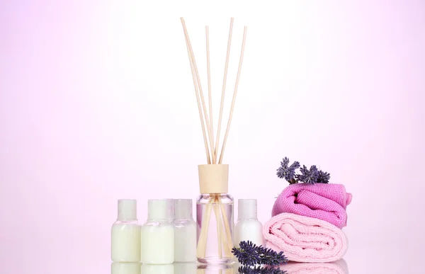 Botella de ambientador, lavanda y toallas sobre fondo rosa —  Fotos de Stock