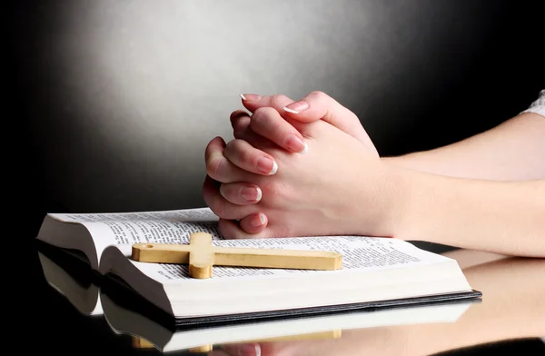 Mãos femininas na bíblia santa russa aberta no fundo preto — Fotografia de Stock