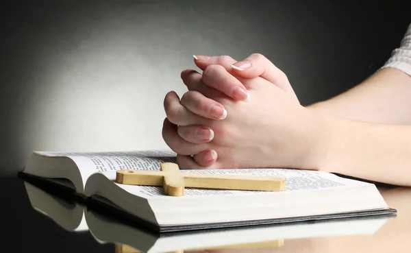 Mãos femininas na bíblia santa russa aberta no fundo preto — Fotografia de Stock