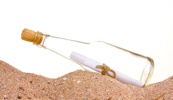 Bouteille en verre avec note à l'intérieur sur sable sur fond blanc — Photo