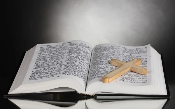 Русская открытая святая Библия с деревянным крестом на черном фоне — стоковое фото
