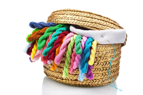 Яскраві нитки для рукоділля і тканини в плетеному кошику — стокове фото