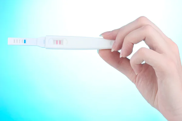Τεστ εγκυμοσύνης στο χέρι σε μπλε φόντο — Φωτογραφία Αρχείου