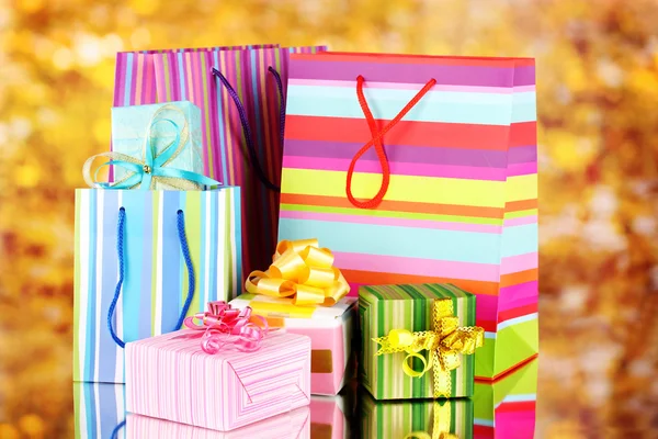Bright gift bags and gifts on yellow background
