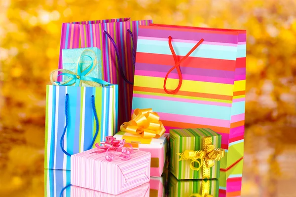Brillantes bolsas de regalo y regalos sobre fondo amarillo —  Fotos de Stock