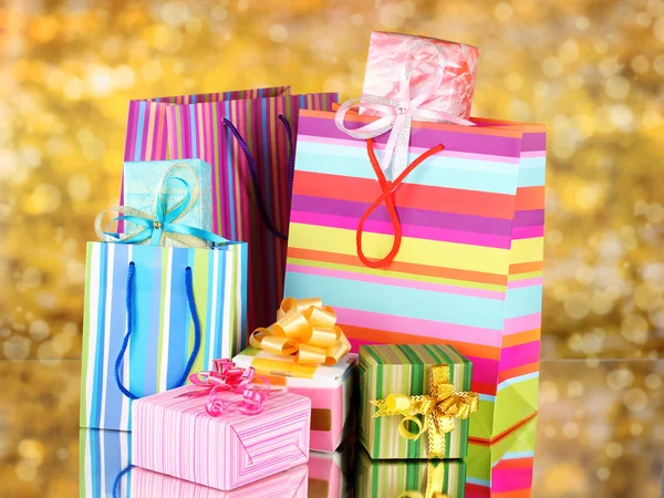 Bright gift bags and gifts on yellow background — Stock Photo, Image