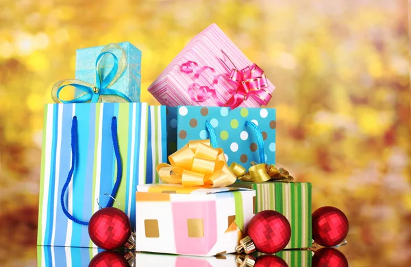 Ljusa presentpåsar och gåvor på gul bakgrund — Stockfoto