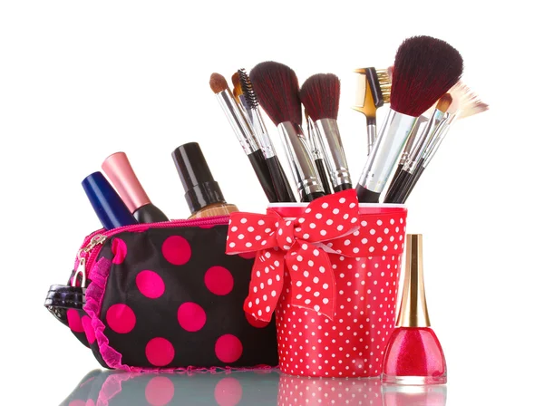 Vidrio rojo con cepillos y bolsa de maquillaje con cosméticos aislados en blanco —  Fotos de Stock