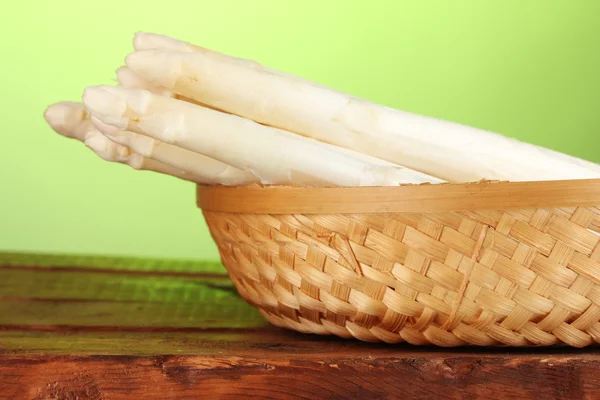 Espargos brancos bonitos na cesta na mesa de madeira no fundo verde — Fotografia de Stock