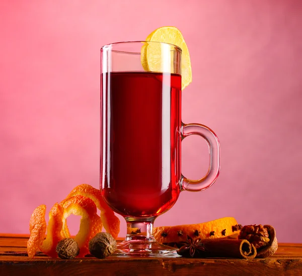 Vin brulè nel bicchiere, spezie e limone su fondo rosa — Foto Stock