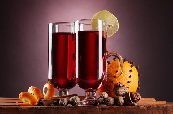 Svařené víno v brýle, koření a oranžové na dřevěný stůl na fialové zpět — Stock fotografie
