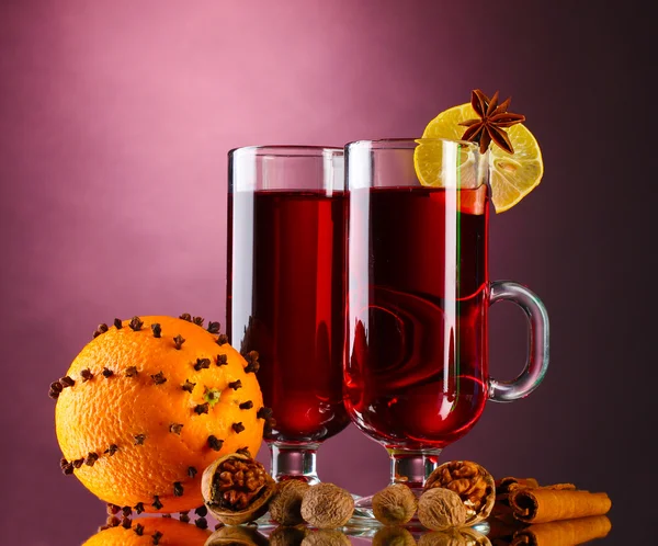 Vin brulè nei bicchieri, spezie e arancia su sfondo viola — Foto Stock